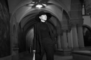 Woman in black suit and black hat under columns