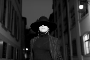 Woman in black suit and black hat at night on street